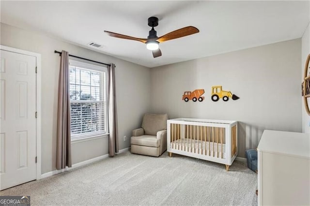 bedroom with a crib, baseboards, visible vents, and carpet floors