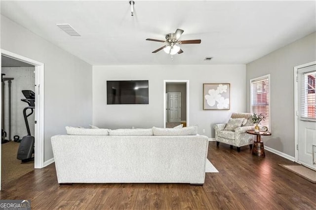 living area with dark wood-style flooring, baseboards, visible vents, and ceiling fan