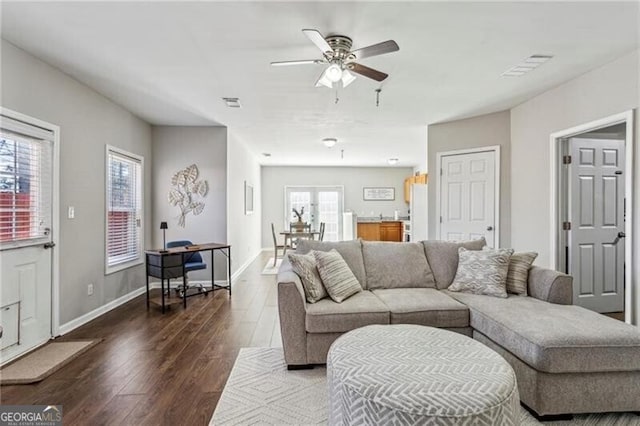 living area with dark wood-style flooring, baseboards, visible vents, and ceiling fan