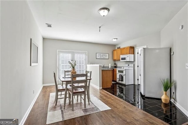 dining area featuring dark wood-style flooring, visible vents, and baseboards
