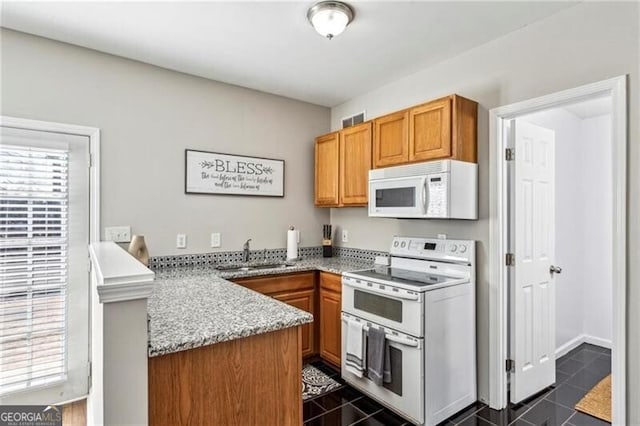 kitchen with a sink, white appliances, a peninsula, brown cabinets, and light stone counters