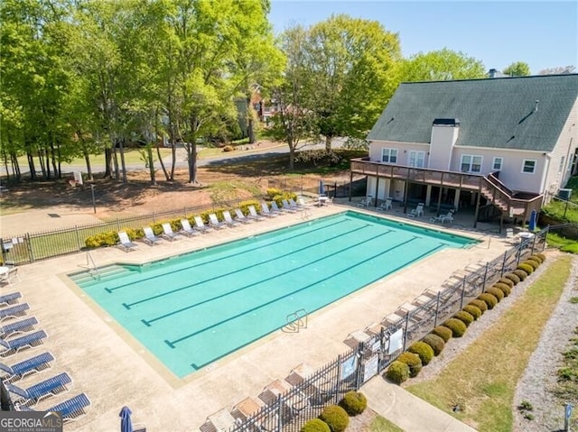 community pool with fence, a patio, and stairway