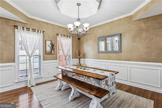 dining area with a chandelier, dark wood-style flooring, a wainscoted wall, and crown molding