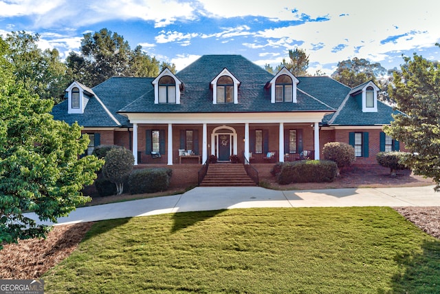 cape cod-style house with a porch, brick siding, and a front yard