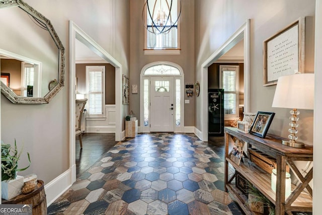 foyer entrance featuring a decorative wall, a wainscoted wall, baseboards, and a towering ceiling