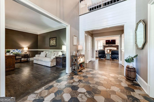 foyer featuring a fireplace, wood finished floors, baseboards, and ornamental molding