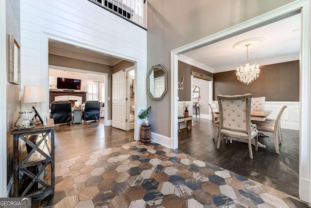 interior space with ornamental molding, a chandelier, wood finished floors, and a wainscoted wall