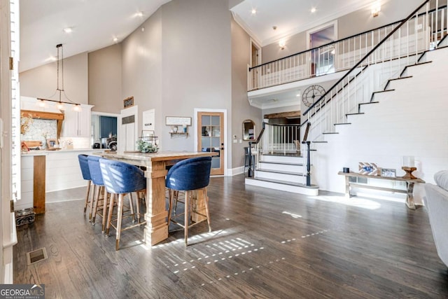 kitchen featuring visible vents, a towering ceiling, white cabinetry, and dark wood-style flooring