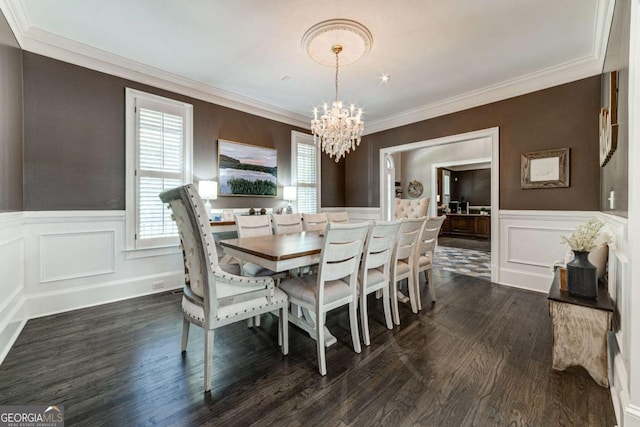 dining area featuring dark wood-style flooring, wainscoting, ornamental molding, and an inviting chandelier