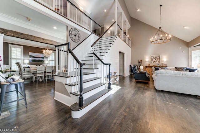 living area with high vaulted ceiling, dark wood-style flooring, stairs, a chandelier, and ornamental molding