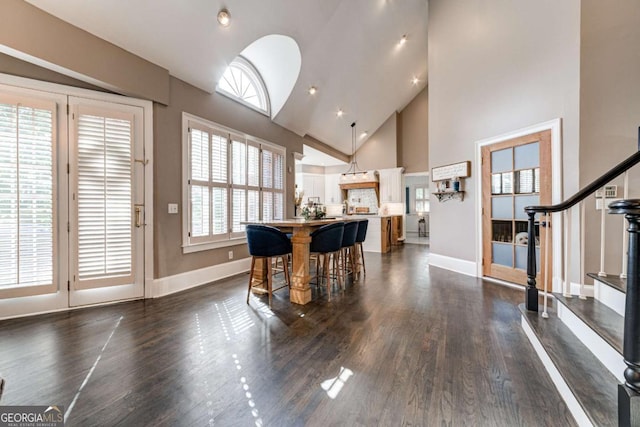 interior space featuring high vaulted ceiling, dark wood finished floors, baseboards, and stairs