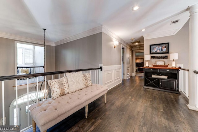 sitting room with a wainscoted wall, crown molding, visible vents, dark wood finished floors, and ornate columns