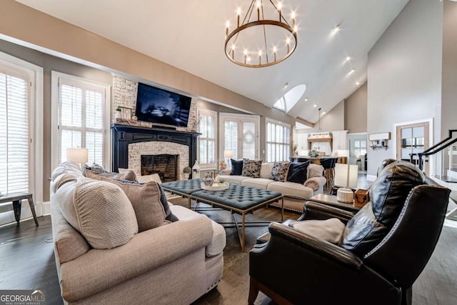 living area featuring dark wood-type flooring, a large fireplace, a notable chandelier, and high vaulted ceiling