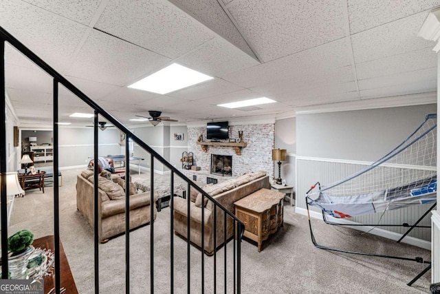 living area with a brick fireplace, carpet flooring, ceiling fan, and a drop ceiling