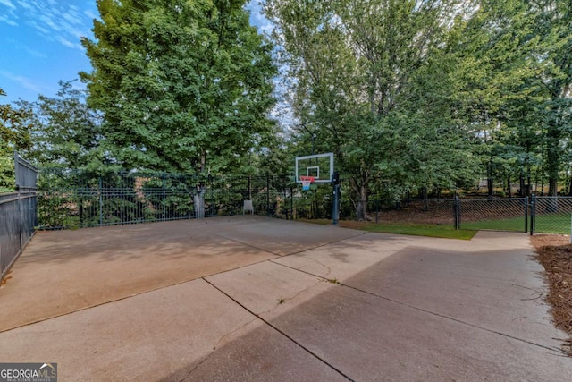 view of basketball court featuring fence and basketball hoop