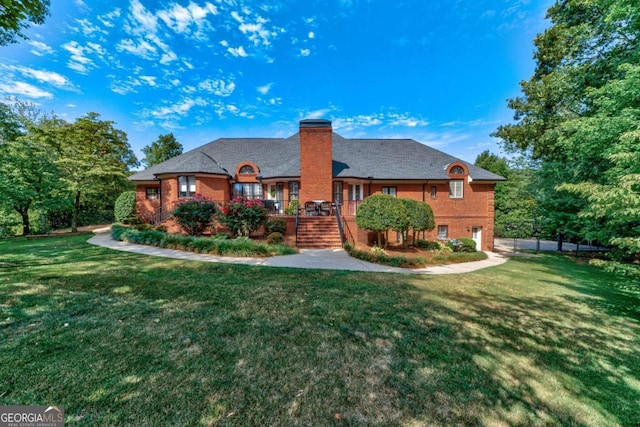 rear view of house with brick siding, a yard, a chimney, and stairs