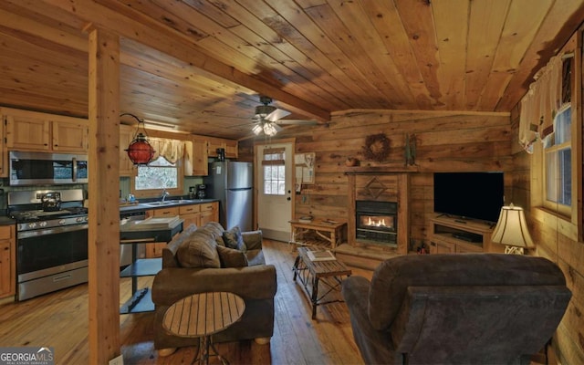 living room featuring a glass covered fireplace, wood walls, wood ceiling, and light wood-type flooring