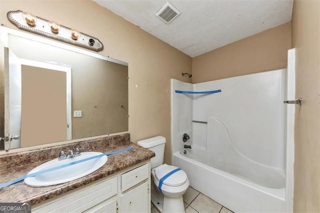 bathroom featuring a textured ceiling, toilet, vanity, visible vents, and tile patterned floors