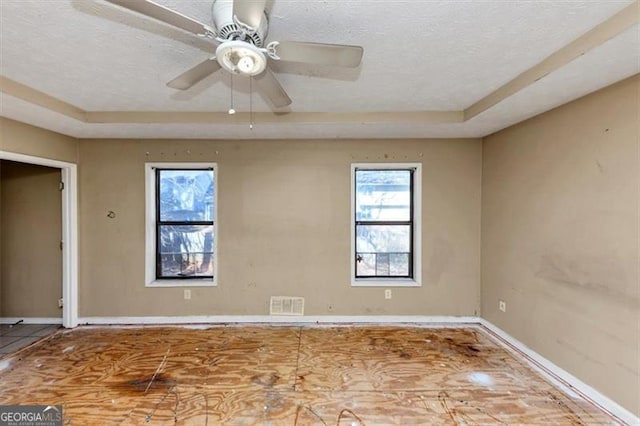 unfurnished room featuring a ceiling fan, visible vents, a textured ceiling, and baseboards