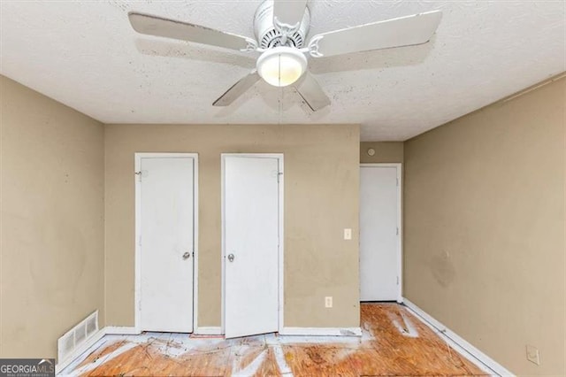 unfurnished bedroom featuring a ceiling fan, visible vents, a textured ceiling, and baseboards