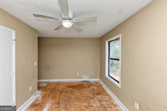 empty room with a ceiling fan, baseboards, visible vents, and a textured ceiling