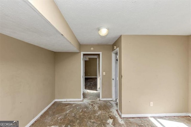 spare room with baseboards and a textured ceiling