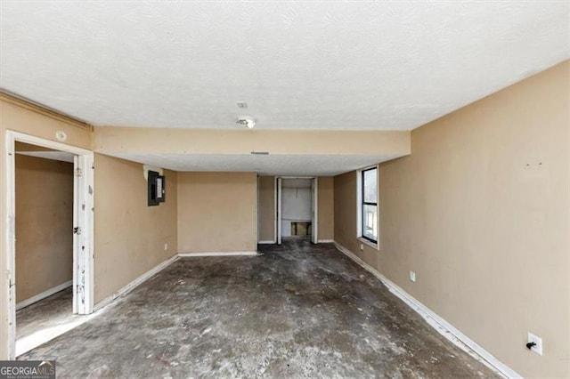 interior space featuring a textured ceiling, unfinished concrete floors, electric panel, and baseboards