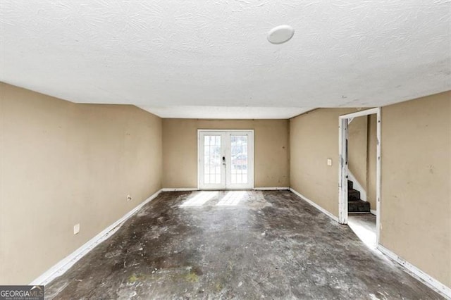 empty room featuring a textured ceiling, french doors, stairway, and baseboards