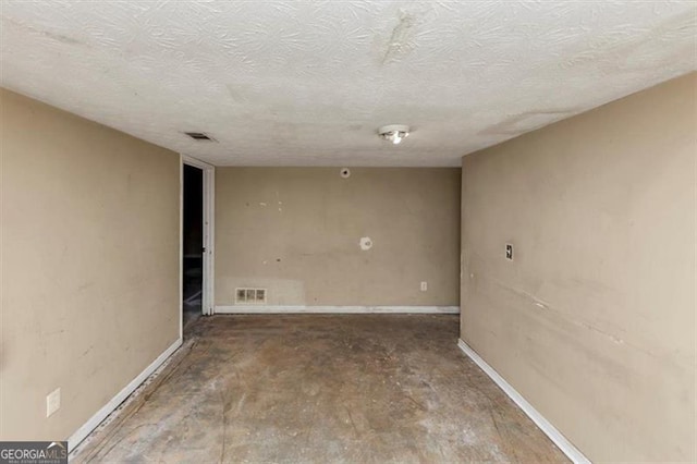 interior space with baseboards, visible vents, unfinished concrete flooring, and a textured ceiling