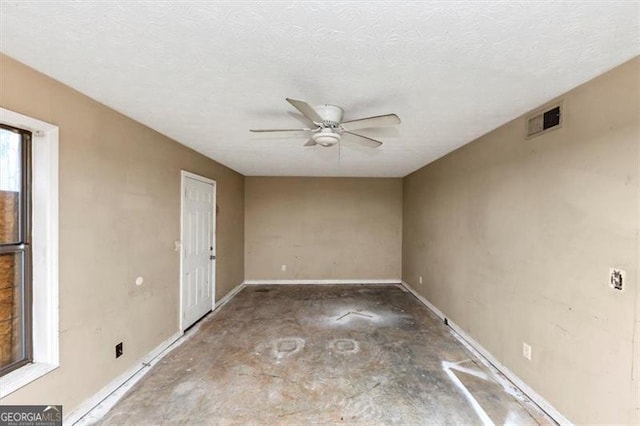 empty room with baseboards, a textured ceiling, visible vents, and a ceiling fan