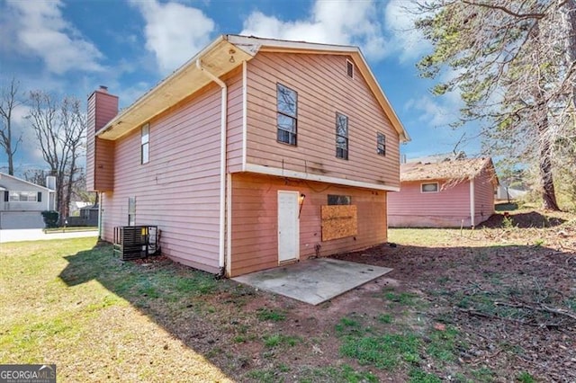 view of side of property with central AC, a patio, a chimney, and a lawn