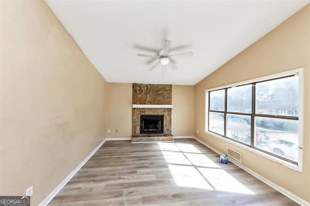 unfurnished living room featuring visible vents, a ceiling fan, lofted ceiling, light wood-style floors, and a fireplace