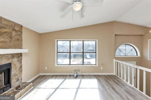 unfurnished living room with a fireplace, wood finished floors, visible vents, baseboards, and vaulted ceiling