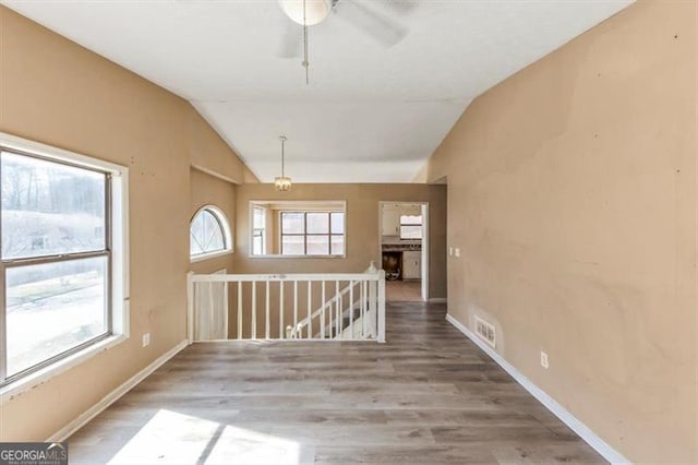 unfurnished room featuring lofted ceiling, baseboards, and wood finished floors