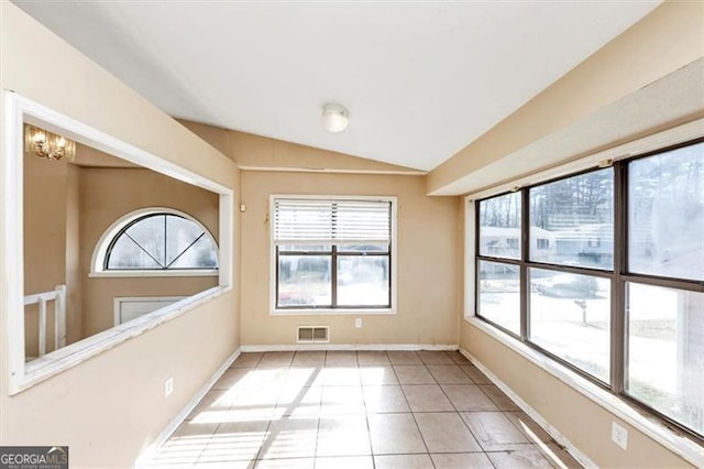 unfurnished room featuring a healthy amount of sunlight, light tile patterned floors, vaulted ceiling, and an inviting chandelier