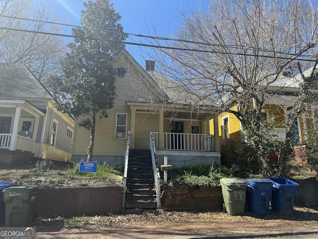 view of front of house featuring covered porch, a chimney, and stairs