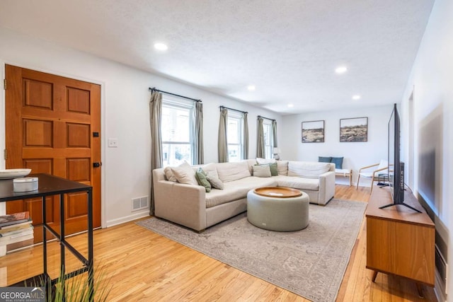 living area featuring a textured ceiling, light wood-style flooring, visible vents, and recessed lighting