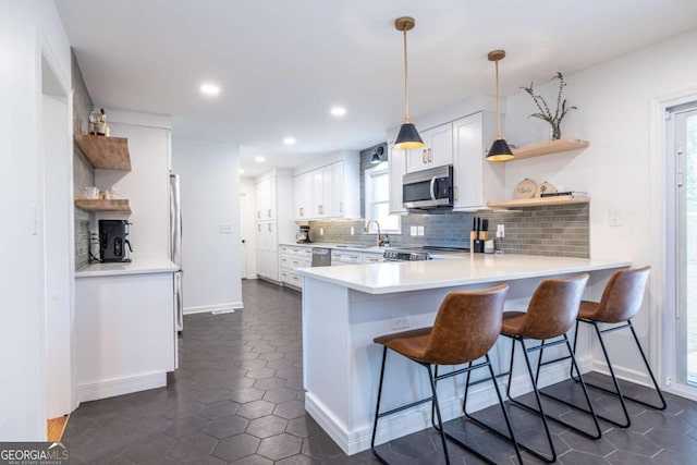 kitchen featuring appliances with stainless steel finishes, a peninsula, decorative backsplash, and open shelves