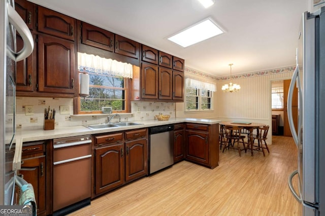 kitchen with stainless steel appliances, light wood finished floors, a sink, and light countertops