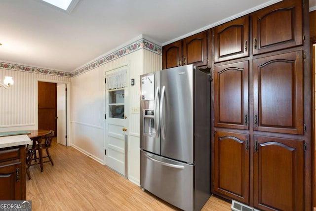 kitchen with light wood-type flooring, wallpapered walls, visible vents, and stainless steel fridge with ice dispenser