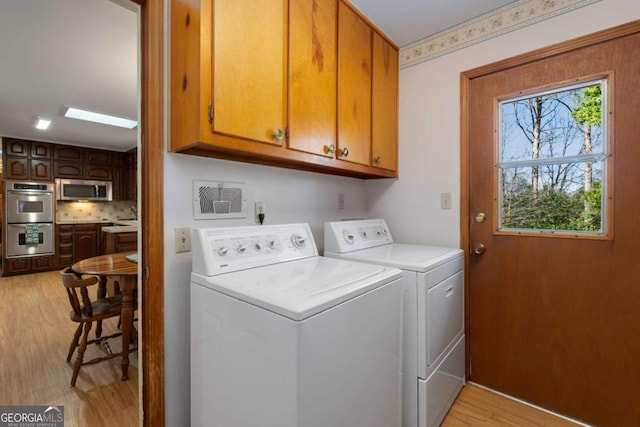 laundry area with cabinet space, washing machine and dryer, visible vents, and light wood-style flooring