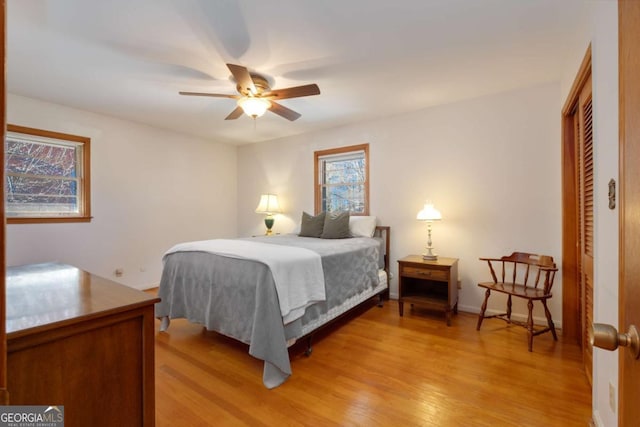 bedroom with light wood-type flooring, a closet, ceiling fan, and baseboards