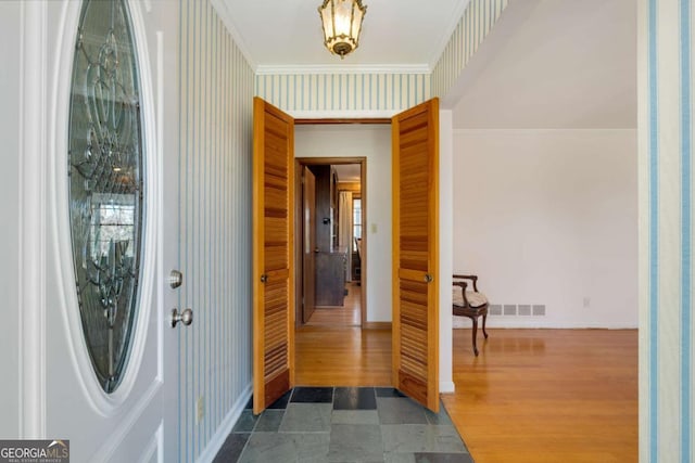 entryway featuring wallpapered walls, baseboards, visible vents, and crown molding