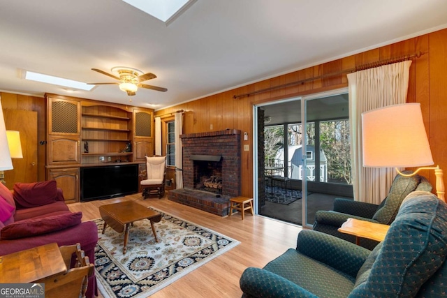 living room featuring a skylight, wooden walls, and ornamental molding