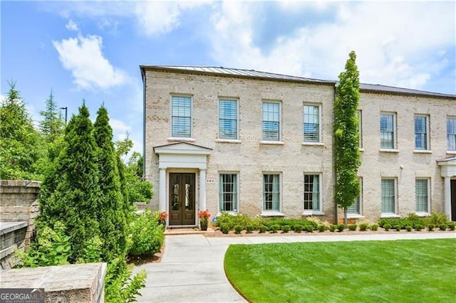 view of front of property featuring french doors, brick siding, a front yard, a standing seam roof, and metal roof