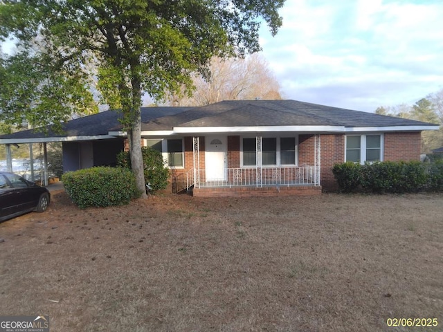 single story home with covered porch, a carport, and brick siding