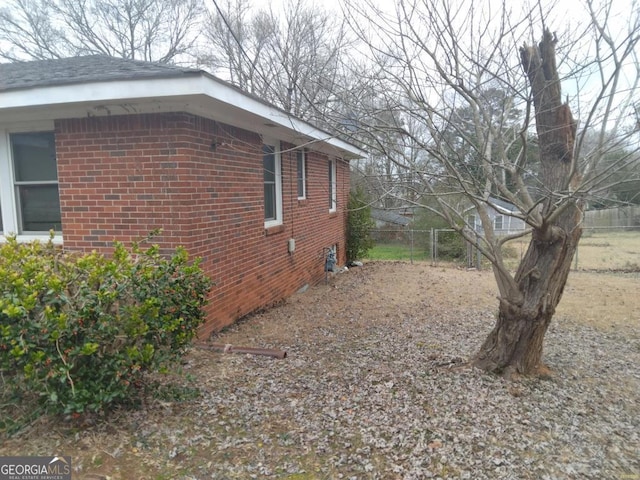 view of side of home with fence and brick siding