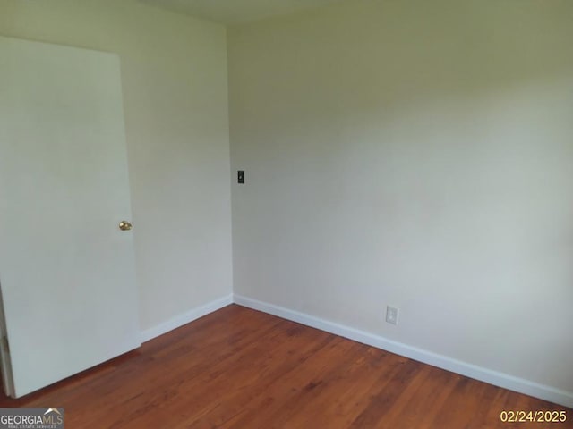 empty room featuring wood finished floors and baseboards