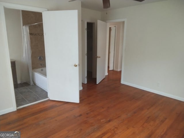 unfurnished bedroom with connected bathroom, baseboards, and wood finished floors