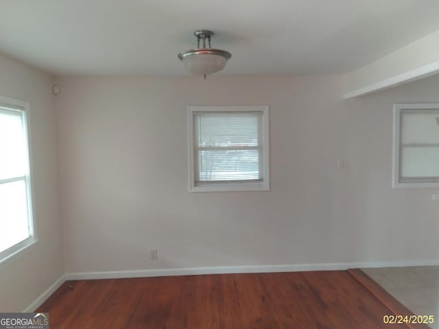 spare room featuring baseboards and wood finished floors